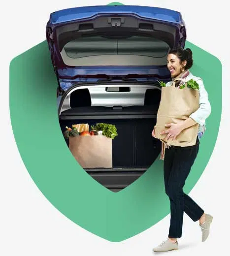 Woman carrying groceries out from the rear trunk of vehicle, with Protect logo sheild surrounding vehicle